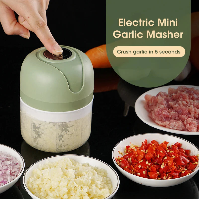 Electric mini garlic masher with garlic and vegetables on a dark surface